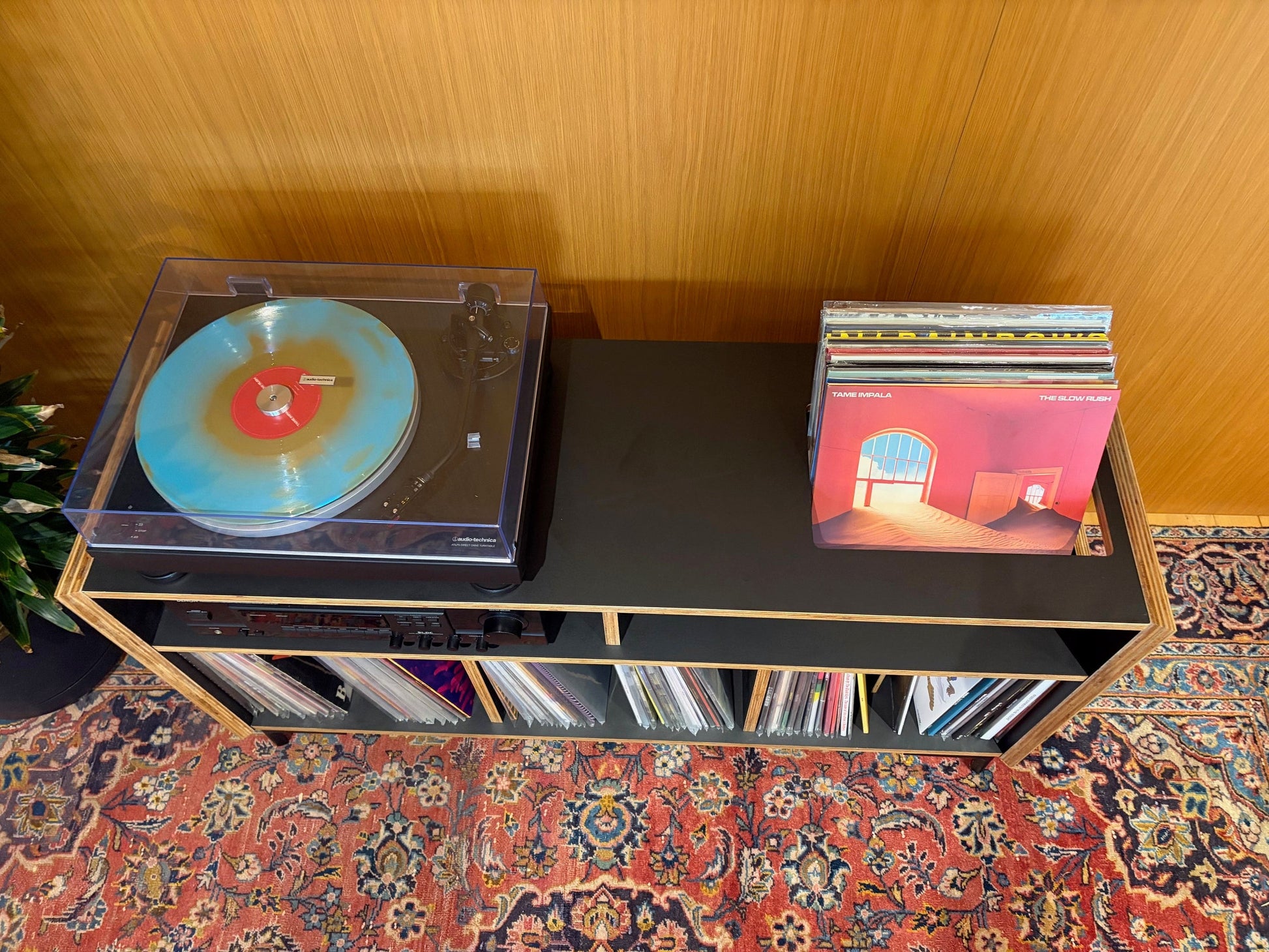 Turntable with a colorful vinyl record on a wooden shelf against a wooden wall.